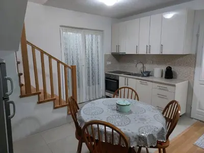 a kitchen with a table and chairs and a kitchen with white cabinets at Holiday Home Adna in Bihać
