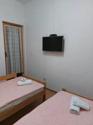 a room with two beds and a tv on the wall at Holiday Home Adna in Bihać