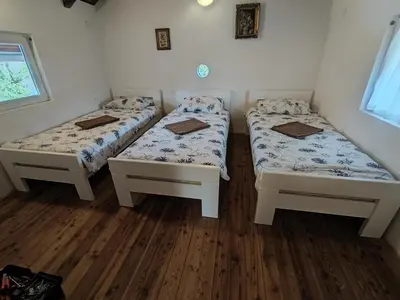 two beds in a room with wooden floors at Kuca Delić in Račić