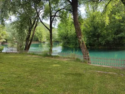 a fence next to a body of water with trees at Kuca Delić in Račić