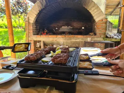 a grill with meat and pastries on a table with a brick oven at Apartment Prole in Šipovo