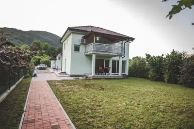 a white house with a balcony and a yard at Villa La Unica in Lohovo