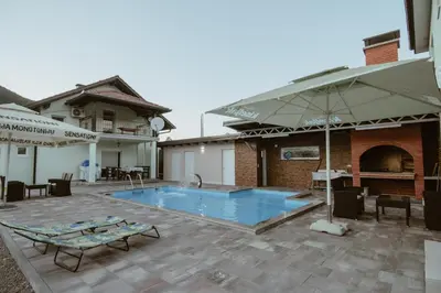 a swimming pool with an umbrella next to a building at Villa La Unica in Lohovo
