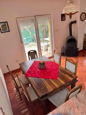 a dining room with a table and a wood stove at Holiday Homer Vila na Obali Vrbasa in Banja Luka