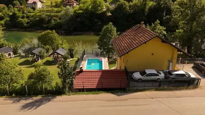 a small house with two cars parked next to a pool at Holiday Homer Vila na Obali Vrbasa in Banja Luka
