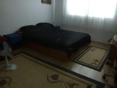 a bedroom with a bed and a rug and a window at Apartman Ela in Bihać