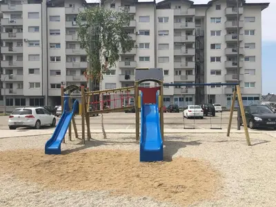 a playground in a parking lot next to a building at Apartment Nesrine in Bihać