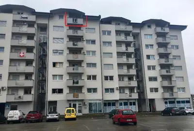 a large apartment building with cars parked in a parking lot at Apartment Nesrine in Bihać