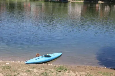 a blue kayak sitting on the shore of a lake at Holiday homes Piralo in Kostajnica
