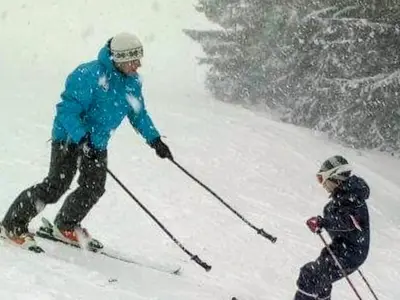 a man and a child skiing down a snow covered slope at Apartments Žera in Vlasic