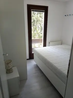 a white bedroom with a bed and a window at Apartments Žera in Vlasic