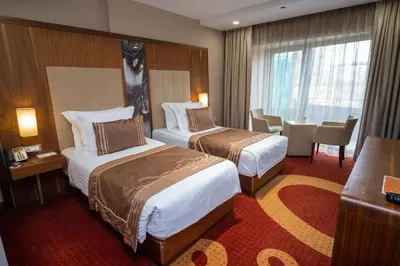 a hotel room with two beds and a table and chairs at Hotel Dubrovnik in Zenica
