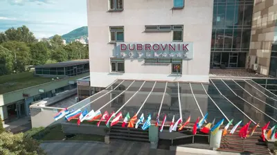 a building with a bunch of flags in front of it at Hotel Dubrovnik in Zenica