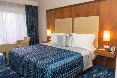 a hotel room with a large bed and a window at Hotel Dubrovnik in Zenica