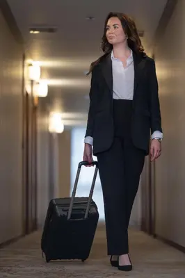 a woman in a suit pulling a suitcase at Hotel Dubrovnik in Zenica