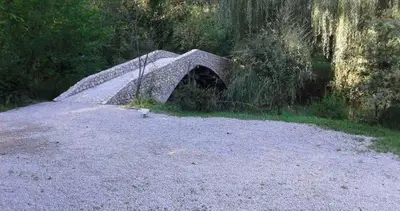 a stone bridge in the middle of a field at Guest House Mala Prica in Živinice