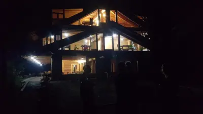 a woman standing in front of a house at night at Guest House Mala Prica in Živinice