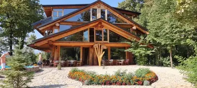 a large wooden house with some flowers in front of it at Guest House Mala Prica in Živinice