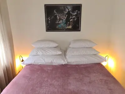 a bed with four pillows and a picture on the wall at City Center Apartment with parking in Banja Luka