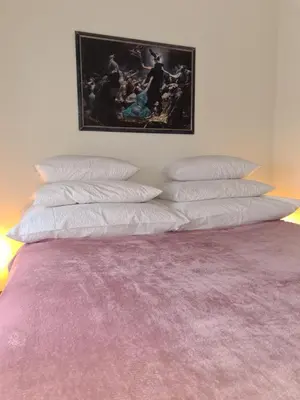 a bed with four pillows on it with a picture on the wall at City Center Apartment with parking in Banja Luka