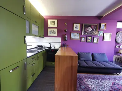a kitchen with purple and green cabinets and a couch at City Center Apartment with parking in Banja Luka