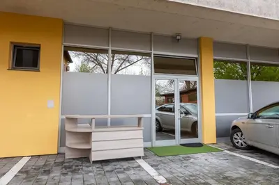 a yellow and white building with a car parked outside at Apartmani i sobe Castra in Banja Luka