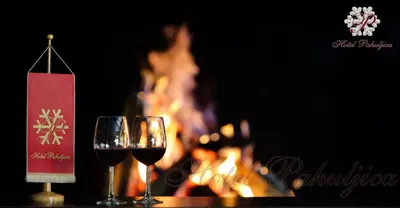 two glasses of red wine sitting next to a fire at Hotel Pahuljica in Vlasic
