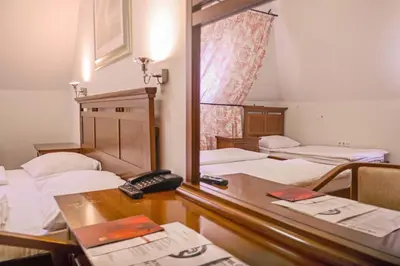 a room with three beds and a desk with a telephone at Hotel Pahuljica in Vlasic