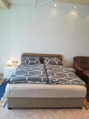 a bedroom with a bed with blue and gray pillows at Prenociste Orhideja in Odžak