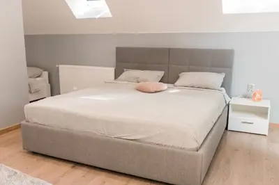 a bedroom with a large bed with a pink pillow on it at Downtown Apartment Travnik in Travnik