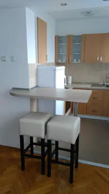 a kitchen with a table with two stools and a refrigerator at Apartman Mima in Banja Luka