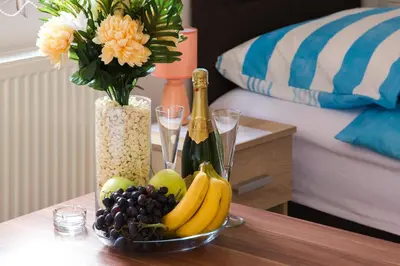 a table with a bowl of fruit and a vase with flowers at Guesthouse Vila Puzic in Banja Luka