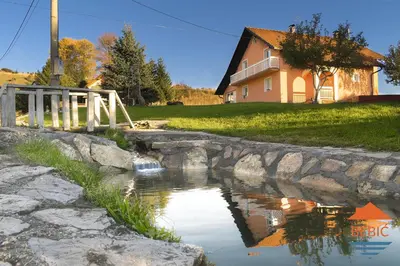 a bridge over a pond in front of a house at Lake House Bebić in Kupres