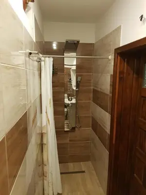 a bathroom with a shower with a phone on the wall at Pansion Renata in Prozor