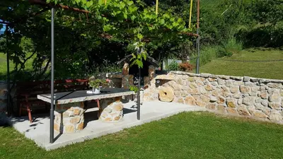 a stone wall and a table in a yard at Pansion Renata in Prozor