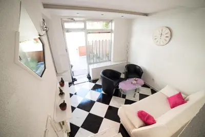 a living room with a couch and a clock on the wall at Apartman Hitno in Tuzla