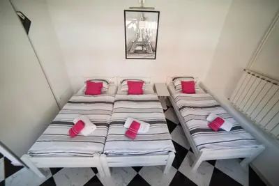 two beds in a small room with red pillows at Apartman Hitno in Tuzla