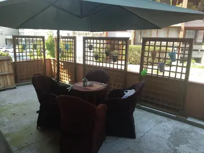 a table and chairs under an umbrella on a patio at Apartman Hitno in Tuzla