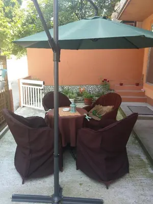 a table and chairs under a green umbrella at Apartman Hitno in Tuzla