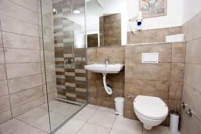 a bathroom with a toilet and a sink and a shower at Hotel Kakanj in Kakanj