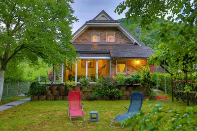 a house with three chairs in the yard at Holiday Home Villa Sara in Bihać