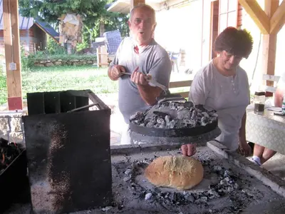 two people standing around a grill with a bread at Smreka Vlašić in Vlasic