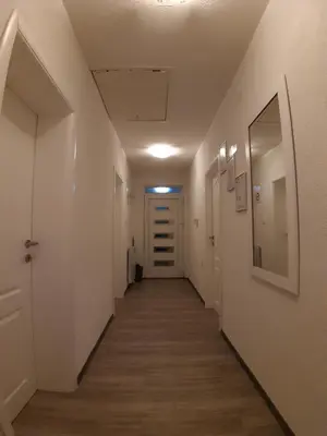 a hallway with a long corridor with white walls and a door at KAĆA APARTMANI 1 in Banja Luka