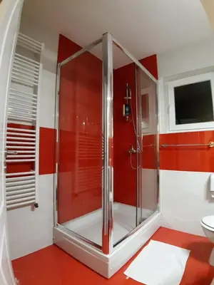 a red and white bathroom with a glass shower at KAĆA APARTMANI 1 in Banja Luka