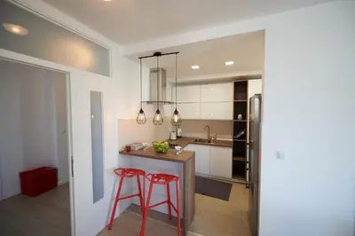 a kitchen with two red bar stools and a refrigerator at Modern luxurious apartment in Banja Luka