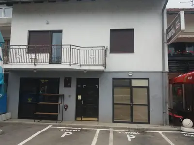 a white building with black doors and a balcony at Rooms Adrijana in Banja Luka