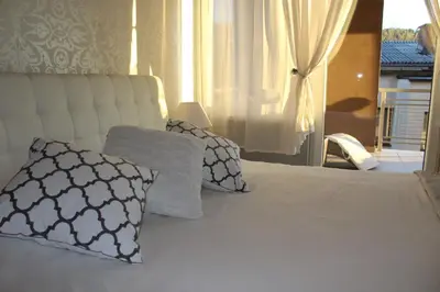 a bedroom with a white bed with pillows and a window at Apartman Diva in Tuzla
