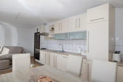 a kitchen with white cabinets and a table and chairs at Apartman Radoš in Kupres