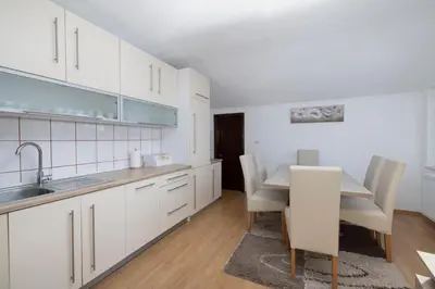 a kitchen with white cabinets and a table and chairs at Apartman Radoš in Kupres