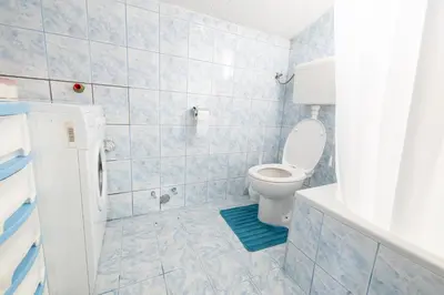 a blue tiled bathroom with a toilet and a shower at Apartman Radoš in Kupres
